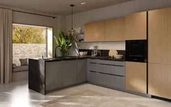 Moderne L‑Küche mit matten grauen Unterschränken, hellen Holzfronten und schwarzer Arbeitsplatte; Insel mit Spülbecken und schwarzem Wasserhahn, integrierter Bosch‑Backofen, Pendelleuchte, große Fensterbank mit Kissen, grüne Zimmerpflanze.